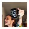 Persona levantando en alto la taza negra mostrando el texto blanco "Lágrimas de mis alumnos" - Happyideas