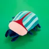 Peluche con forma de escarabajo en tonos rosa y azul a rayas, fotografiado en perspectiva sobre fondo verde liso - Happyideas