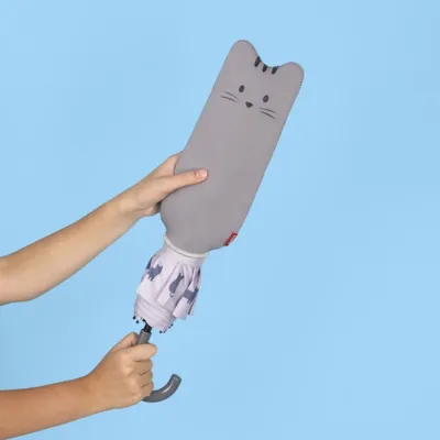 Mano sujetando el paraguas Meow cerrado con funda con forma de cabeza de gato gris, sobre fondo oscuro - Happyideas