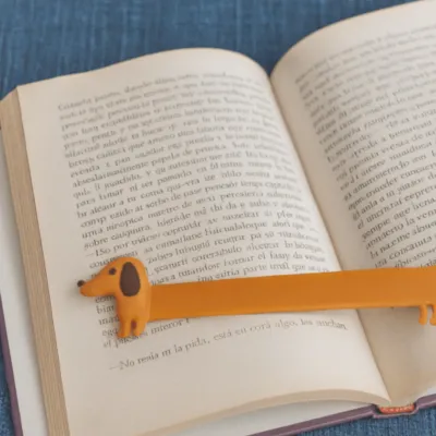 Marcapáginas con forma de perro Teckel color naranja, colocado sobre un libro abierto - Happyideas
