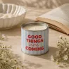 Vela en lata Good Things Are Coming con un libro y flores