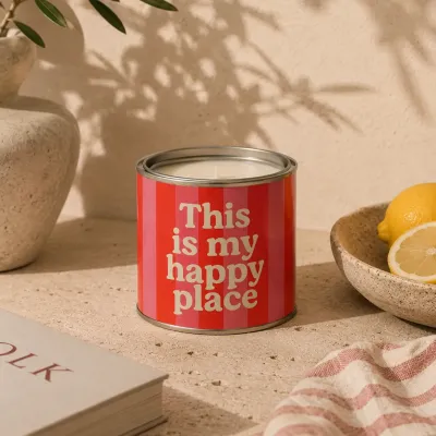 Vela en lata This Is My Happy Place encendida sobre una mesa con limones