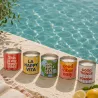 Colección de velas en lata con mensajes positivos de Happyideas junto a la piscina