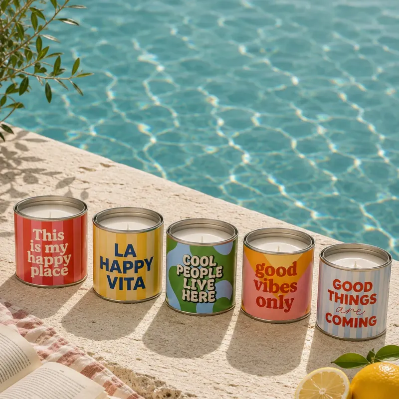 Colección de velas en lata con mensajes positivos de Happyideas junto a la piscina