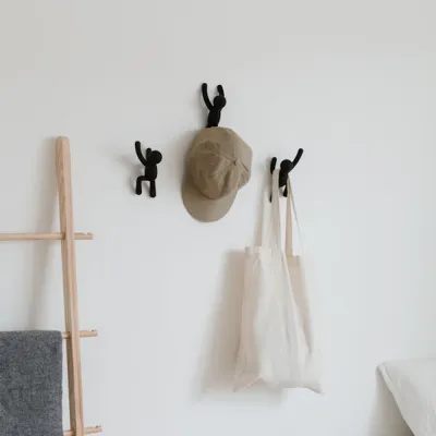 Perchas Buddy negras colocadas en la pared con un abrigo colgado