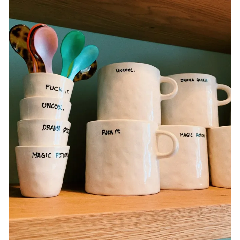 Taza Fuck It, en una estantería junto a otras tazas con mensaje de la colección - Happyideas