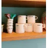 Taza Fuck It, vista de la colección completa de tazas con mensaje sobre una mesa de madera - Happyideas