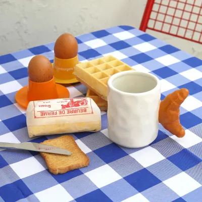 Taza Croissant, portada del producto sobre un mantel de cuadros con un cruasán - Happyideas