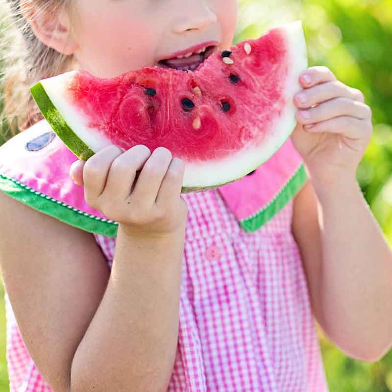 Niña comiendo una pieza de fruta