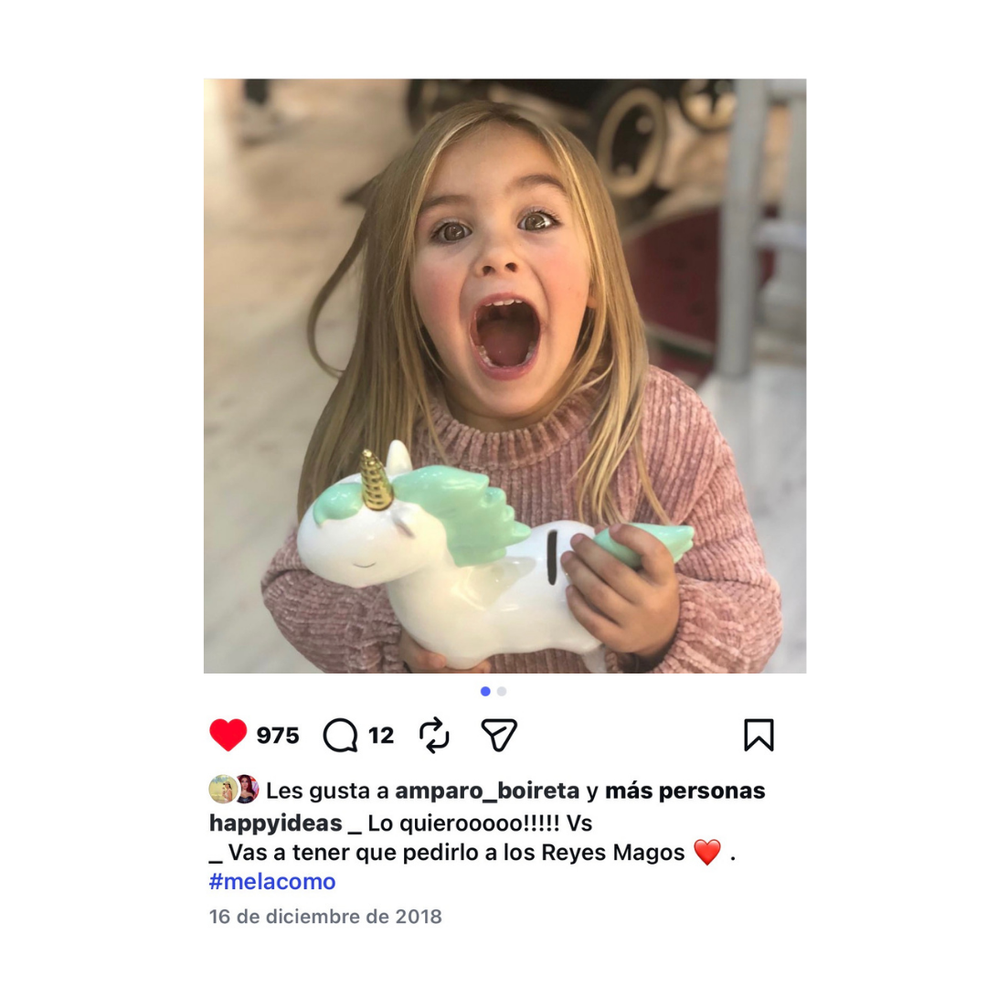 Niña con cara de ilusión sosteniendo una hucha unicornio de Happyideas