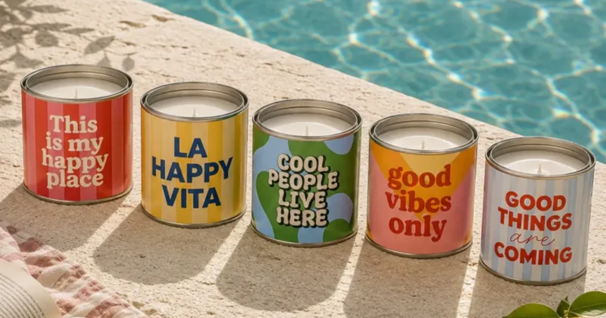 Las cinco Happy Velas aromáticas en lata de Happyideas encendidas al borde de una piscina