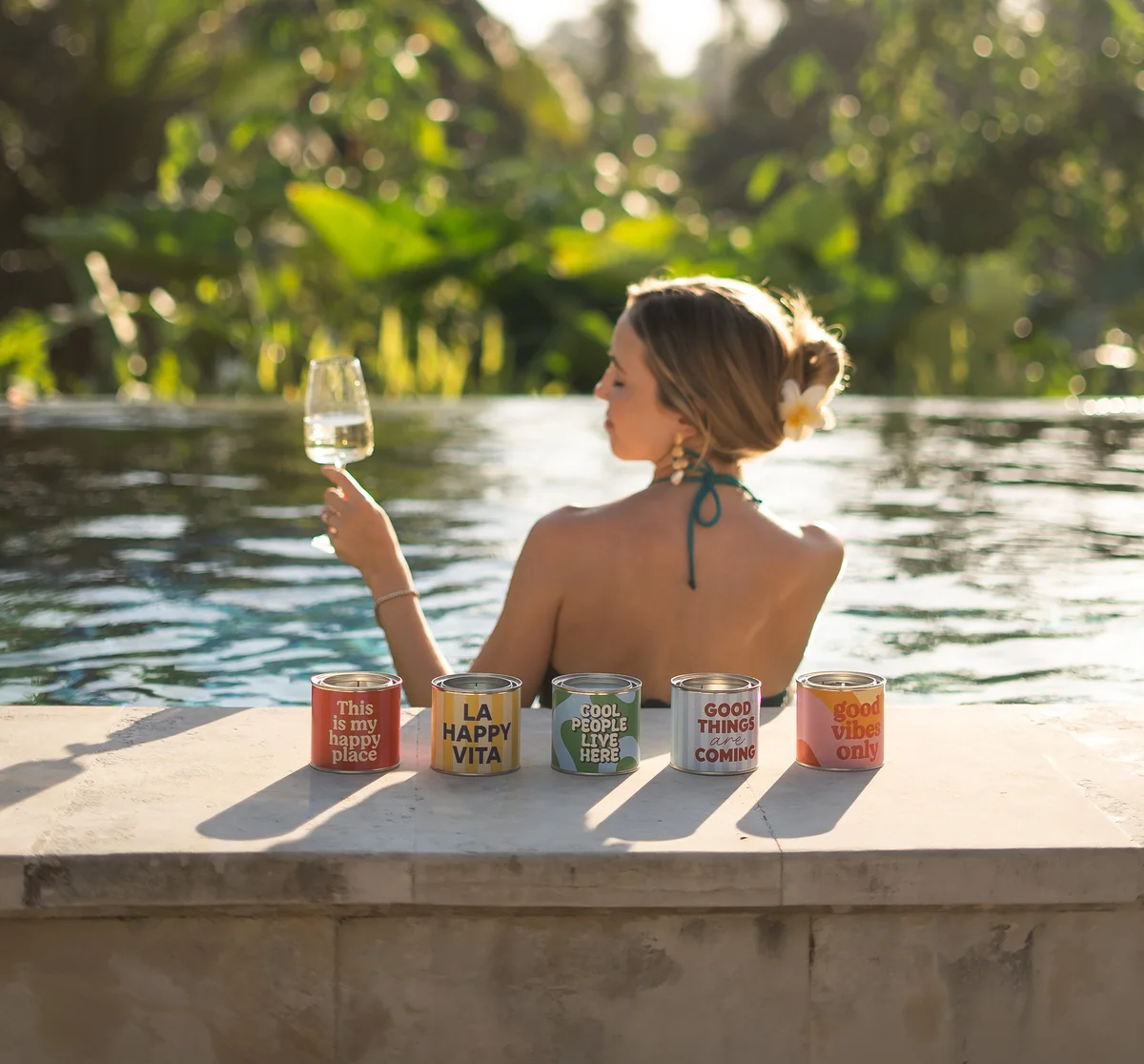 Las cinco Happy Velas, velas aromáticas en lata de Happyideas, al borde de una piscina en Ubud, Bali