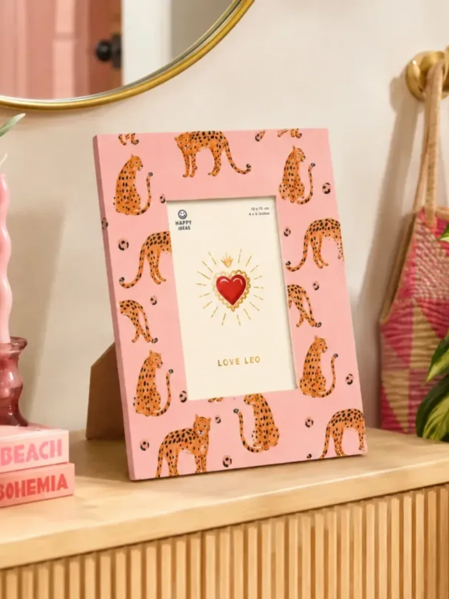 Marco de fotos rosa con leopardos sobre una cómoda de madera